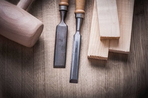 Wooden bricks mallet carpenter??™s flat chisels on wood background construction concept