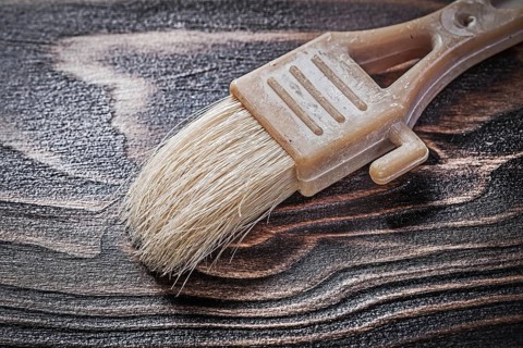 Obsolete paintbrush on wood board close up view construction concept