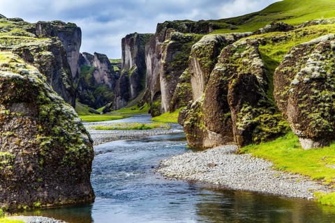 The sheer cliffs covered with green moss enclose the channel of the brook with melted water. The