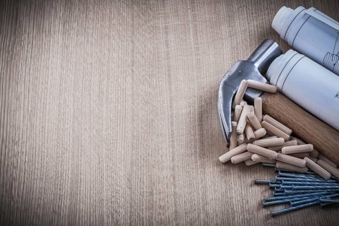 Blueprints hammer dowels nails on wooden board construction concept