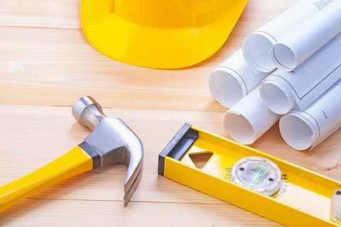 Claw hammer rolled blueprints construction level hardhat on wooden boards horizontal version