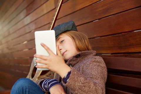 Blond kid girl taking selfie with guitar and winter beret and coat on wooden background