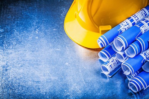 Blue blueprints hard hat on metallic background construction concept