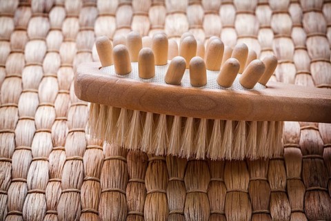 Close up image of wooden massager with scrubbing brush on wicker background healthcare concept