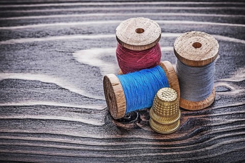 Vintage reels of thread thimbles on wooden board handicraft concept