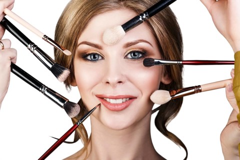 Many hands with cosmetics brushes doing make-up to glamour woman, over white background