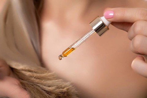 A closeup view of a dropper filled with luxurious hair oil, emphasizing its nourishing and