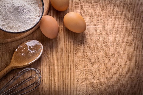 Organized copyspace eggs flour in bowl spoon corolla on wooden board food and drink concept