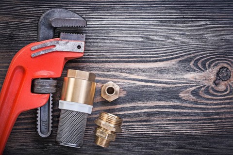Pipe wrench check valve with strainer filter hose nipples on wooden board