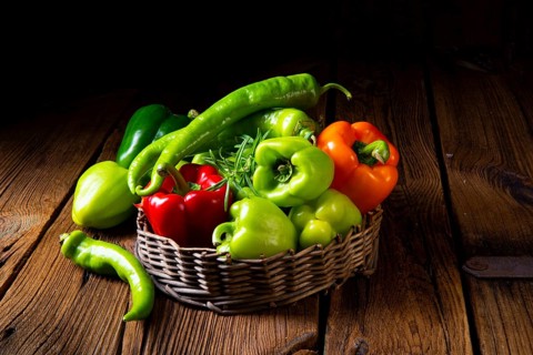 Various harvested peppers and hot peppers in basket