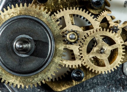 Close up metal gears mechanism. Golden colours. Hard light. Clock interior mechanism parts
