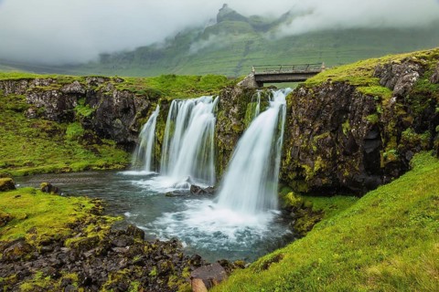 Threaded full-flowing waterfall on the grassy mountains. Iceland - country of mountains, rivers and