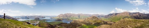 View over a wide mountain landscape with lakes and green terrain under a clear sky, Wanaka, New
