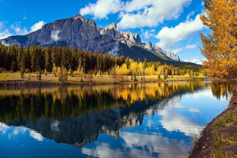 Outskirts of Canmore. Lush autumn in the Canadian Rockies. Cumulus clouds reflected in the smooth