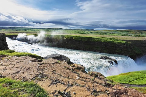Iceland. Grand Gullfoss. In mid-July, bubbling water illuminated by a bright morning sun