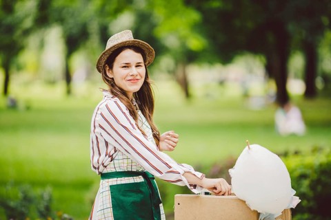 Photo theme small business cooking sweets. A young caucasian woman with an apron trader in the hat