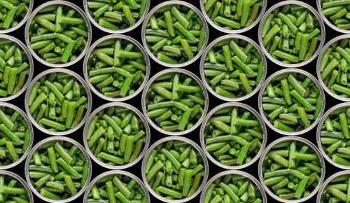 Seamless food background of flat lay view at opened tin cans with green beans isolated on black