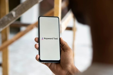 keyword tool logo is displayed on smartphone. Keyword Tool is a free online keyword research tool
