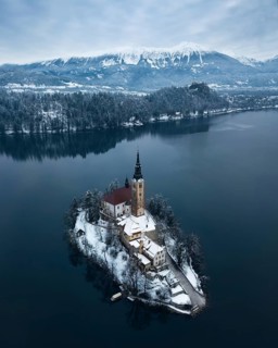 Aerial shot of lake Bled on a calm winter morning with snow