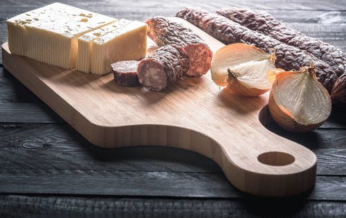 Tasty meal with homemade smoked sausages from beef and pork, fresh cheese and onion, displayed on a