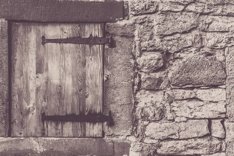 Architectural frame with a weathered wooden trap door and the stone wall, from a traditional german