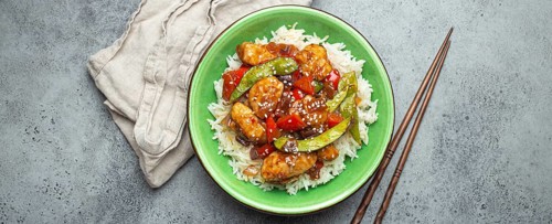 Asian sweet and sour sticky chicken with vegetables stir-fry and rice in ceramic bowl with