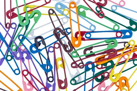 Many colourful safety pins lie on a white background Austria