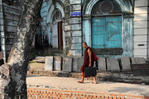 07.10.2013, Yangon, Myanmar, Asia, A Buddhist monk walks with his briefcase past an old colonial