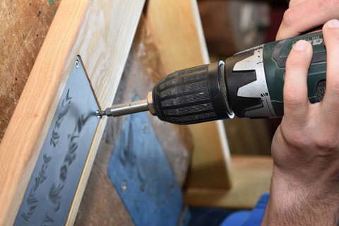 Craftsman working on wood with a drill - close-up carpenter