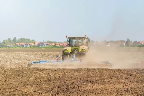 Farmer in tractor preparing land seedbed cultivator. Agriculture tractor landscape