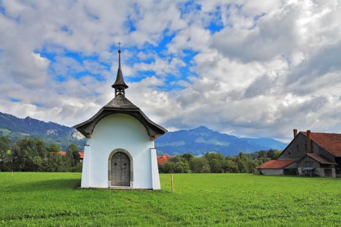 Small rural chapel on a green meadow. Picturesque forged door decorated rows of round rivets. A