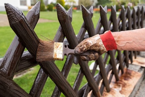 Person painting their wooden garden fence - close-up of classic hunter fence