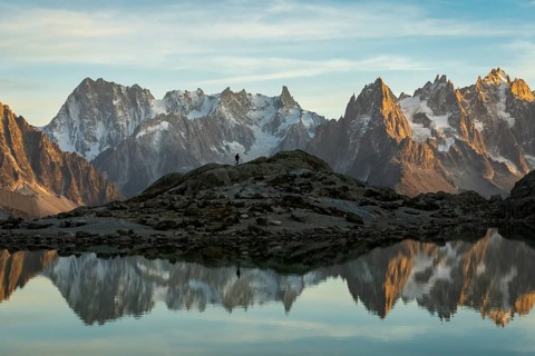 Silhouette of Hiker, Mountains and Reflection in Lac Blanc Lake at Sunset. Golden Hour. French