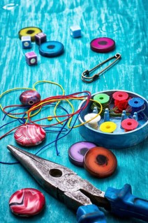 Coil, beads and tools for needlework on turquoise wooden background