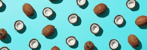 Creative layout of coconuts half on blue background. Tropical pattern, top view or flat lay. Hard