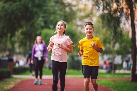 Sports and fitness in adolescence. Caucasian twins boy and girl run on the jogging track in the