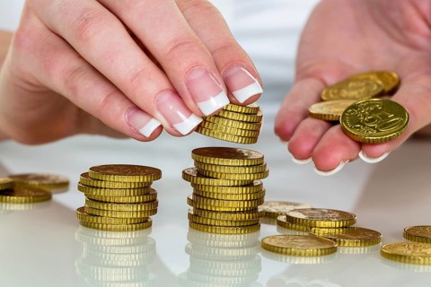 A woman stacks coins. Saving money for the future. Austria