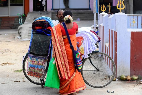 Kanchipuram, Tamil Nadu, South India, A traditionally dressed woman carries colourful fabrics on a