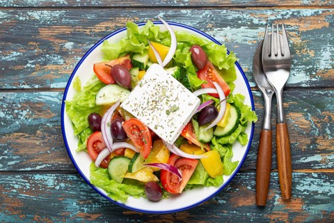 Traditional Greek Salad with Feta Cheese, Tomatoes, Bell Pepper, Cucumbers, Olives, Herbs in white