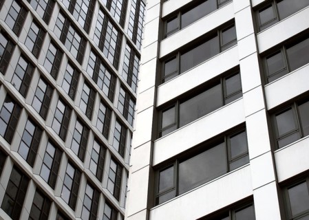 Close up detail of tall high rose modern apartment buildings with white cladding and dark windows