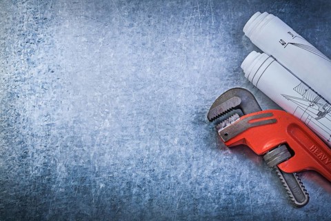 Monkey wrench construction plans on metallic background plumbing concept