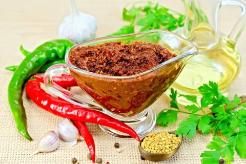 Tabasco adjika in a glass gravy boat, hot pepper, garlic, parsley, fenugreek, oil in the decanter