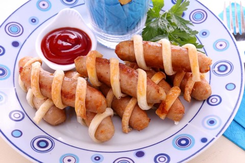 Twisted pastry around chicken sausages with ketchup