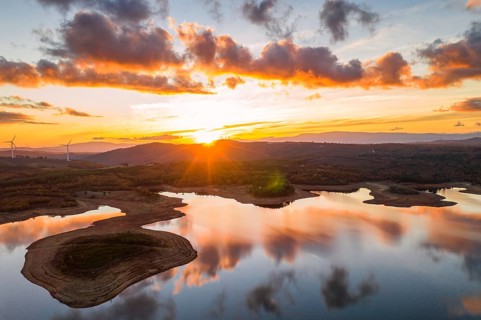 Drone aerial view of a lake reservoir of a dam with perfect reflection on the water of the sunset