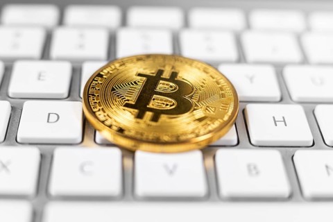 Bitcoin coin lying on white computer keyboard