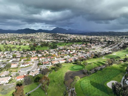 Aerial view of residential neighborhood surrounded by golf and valley during cloudy day in Rancho