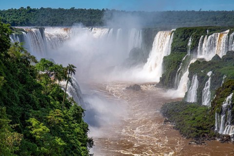View to Devil's Throat and Iguazu Falls gorge with brown river, white cascading falls and lush