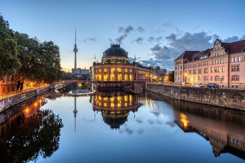 The Bode Museum and the television tower are reflected in the Spree in Berlin in front of sunrise