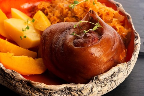 Appetizing baked pork knuckle with potatoes and cabbage on plate