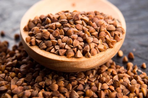 Buckwheat seeds on wooden spoon in closeup, lodz, poland